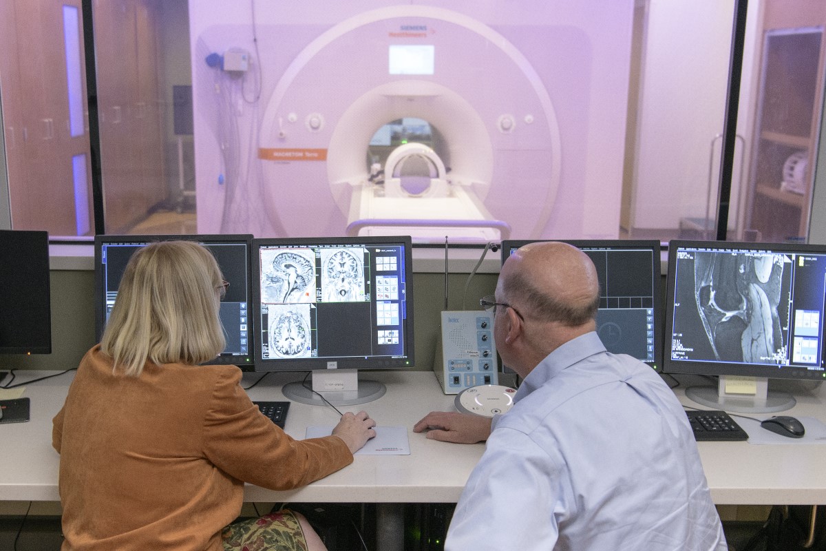 Two people in MRI control room looking at computer screens